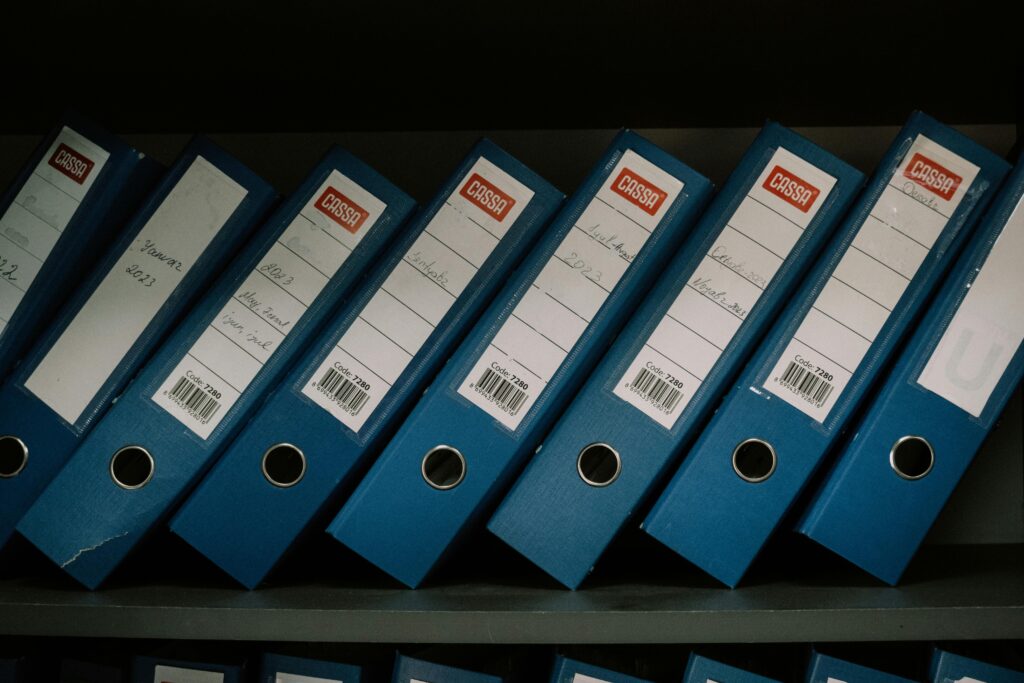 Neatly arranged blue office binders labeled with dates and names for organized storage.